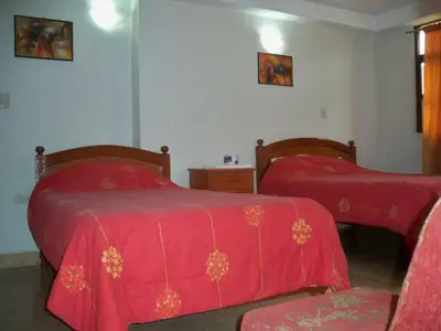 a bedroom with two beds with red covers and a chair at El Balcon Hostal in Ayacucho