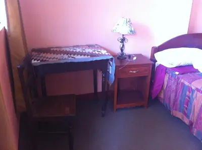 a bedroom with a desk and a bed and a lamp at Hostal Tres Máscaras in Ayacucho