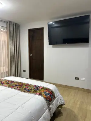 a bedroom with a bed with a flat screen tv on the wall at Skyhousecusco in Cusco