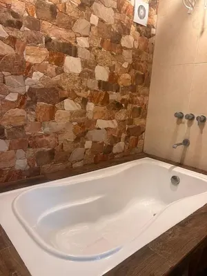 a white bath tub in a bathroom with a stone wall at Skyhousecusco in Cusco