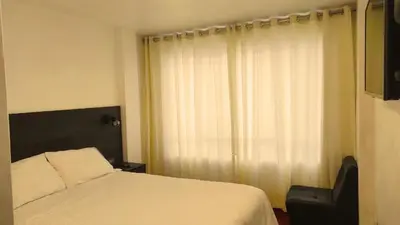 a bedroom with a bed and a chair next to a window at Apartamento Andahuaylas in Andahuaylas