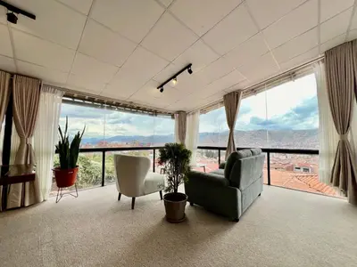 a living room with a couch and chairs and large windows at Casa Encuentro San Blas in Cusco