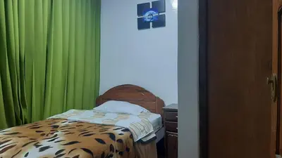 a bedroom with a bed with green curtains and a bedskirtspectspectspectspects at Sierra Verde - Muy Céntrico Hs in Huancayo