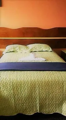 a bed with a wooden headboard and two pillows at Sierra Verde - Muy Céntrico Hs in Huancayo