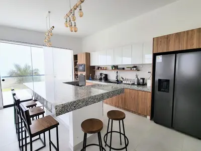 a kitchen with a large counter and stools in it at HERMOSA CASA CON PISCINA FRENTE AL MAR - PRIMERA FILA in Chincha Baja