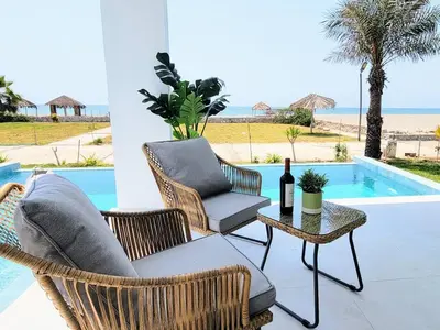 a patio with chairs and a table with a bottle of wine at HERMOSA CASA CON PISCINA FRENTE AL MAR - PRIMERA FILA in Chincha Baja