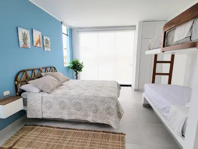 a bedroom with two beds and a blue wall at HERMOSA CASA CON PISCINA FRENTE AL MAR - PRIMERA FILA in Chincha Baja
