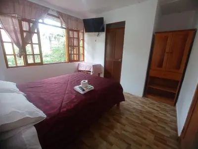 a bedroom with a bed with a cup of coffee on it at Hospedaje Pinky Lodge in Oxapampa