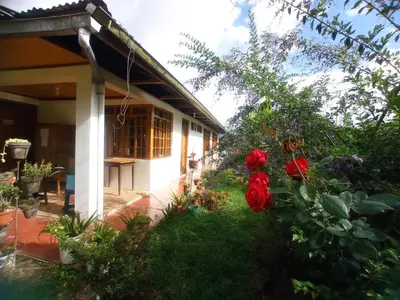 a house with red flowers in the yard at Hospedaje Pinky Lodge in Oxapampa