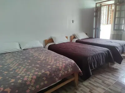 a room with three beds in a room at Hospedaje Pinky Lodge in Oxapampa