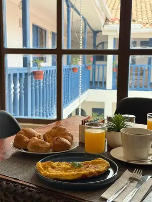 a table with a plate of breakfast food and orange juice at Casa Tiyay Cusco in Cusco
