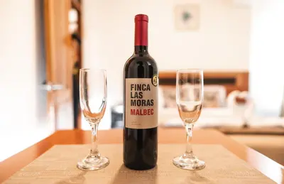 a bottle of wine and two glasses on a table at Escobedo’s Inn Machupicchu in Machu Picchu