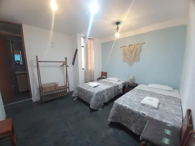 a room with two beds in a room with a window at Hospedaje Hamuy's Lodge in Ica