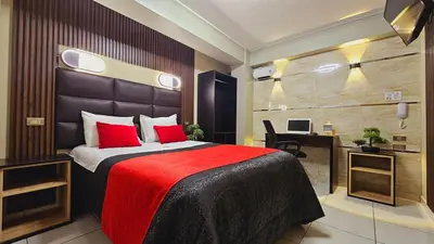 a bedroom with a bed with red pillows and a desk at Hotel del Valle in Huancayo