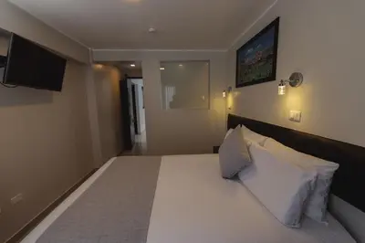 a bedroom with a large white bed with a tv on the wall at Classic Hotel Cusco in Cusco