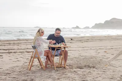 a man and woman sitting at a table on the beach at Acari Adventure & ski Resort in Acarí