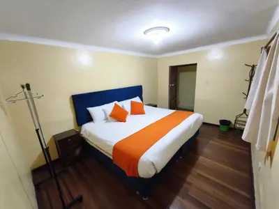 a bedroom with a large bed with orange pillows at Qosqo Apartments 3 in Cusco