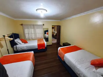 a hotel room with two beds with orange and white at Qosqo Apartments 3 in Cusco