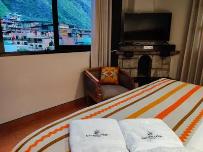 a bedroom with a bed with a fireplace and a television at NaturaLodge Machu Picchu in Machu Picchu