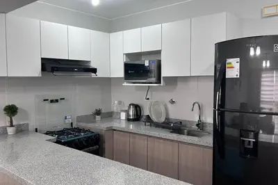 a kitchen with white cabinets and a black refrigerator at Departamento de Estreno - cerca a la Playa in Lima