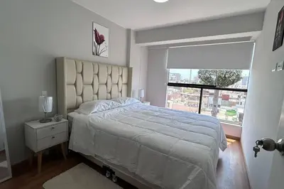 a bedroom with a large bed and a window at Departamento de Estreno - cerca a la Playa in Lima