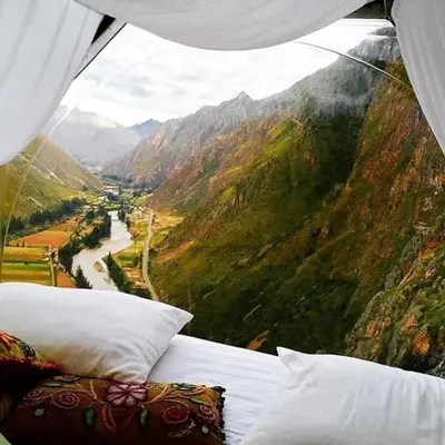 a bed with pillows and a view of a mountain at Skylodge Adventure Suites in Urubamba