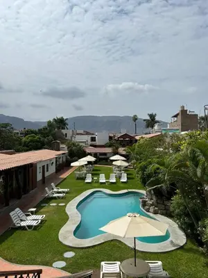 a swimming pool with an umbrella and lounge chairs at Oro Viejo in Nazca