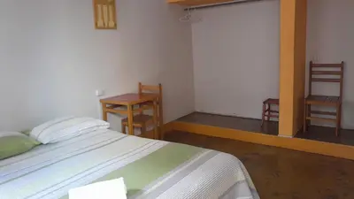 a bedroom with a bed and a table and two chairs at Brabant Hostal in Nazca