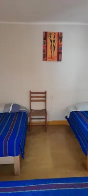 a room with two beds and a chair in it at Brabant Hostal in Nazca