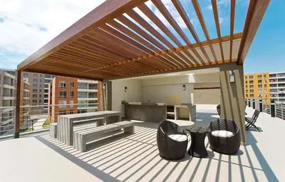 a wooden pergola on a deck with chairs and a table at Bonito departamento VIP estreno en Condominio in Lima