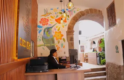 a woman sitting at a desk with a laptop at Cusco Lodge Hotel Boutique in Cusco