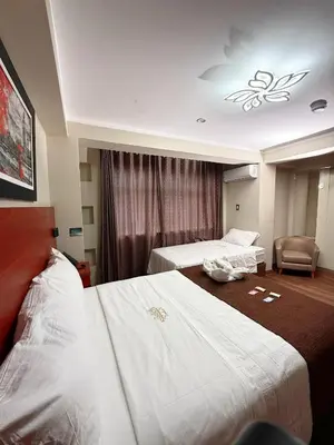 a hotel room with two beds and a chair at Hotel Kapadokya in Huánuco