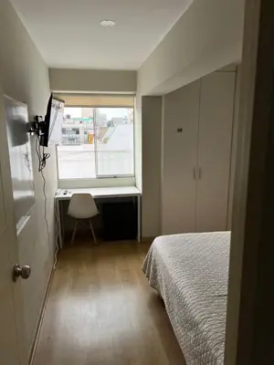 a bedroom with a bed and a desk and a window at Departamento 17 personas San Isidro in Lima