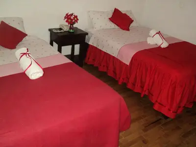 two beds in a room with red and white sheets at Hotel Conquistadores Inn in Ica