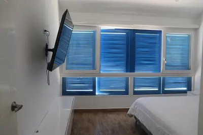 a bedroom with blue shutters on a window at Casa Z Paracas in Paracas