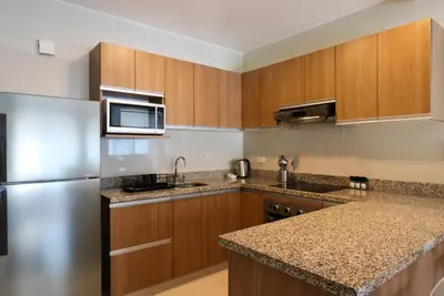 a kitchen with wooden cabinets and a stainless steel refrigerator at Narciso 350 by Wynwood House in Lima