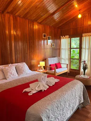 a bedroom with a large bed with a red blanket at Carolina Egg Gasthaus in Oxapampa