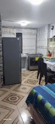 a room with a kitchen with a refrigerator and a table at LA POSADA CHASQUI INN en LIMA in Lima