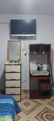 a bedroom with a tv and a dresser with a flower in at LA POSADA CHASQUI INN en LIMA in Lima