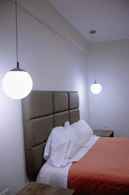 a bedroom with a bed with two lights above it at PRANA in Huancayo