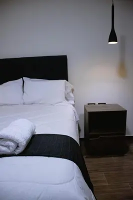 a bedroom with a white bed and a night stand at PRANA in Huancayo