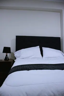 a bedroom with a white bed with a black headboard at PRANA HOTEL LOUNGUE BAR in Huancayo