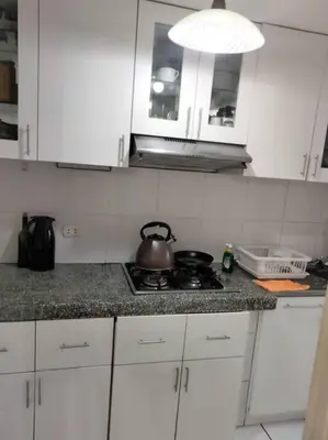 a kitchen with white cabinets and a tea kettle on a stove at Tait's House - Cómodo departamento Dúplex - Ate in Lima