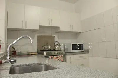 a white kitchen with a sink and a microwave at Inti Wasi in Cusco