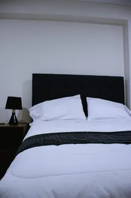 a bedroom with a white bed with a black headboard at PRANA in Huancayo
