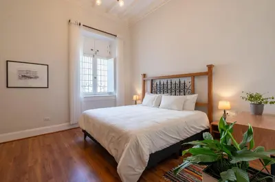 a bedroom with a bed with white sheets and a window at Casa Cáceres in Lima