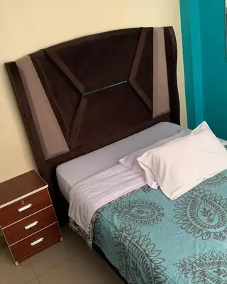 a bed with a wooden headboard and a night stand at HOSTAL TOSCANO SUITES in El Tambo