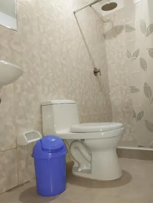 a bathroom with a toilet and a blue trash can at HOSTAL TOSCANO SUITES in El Tambo