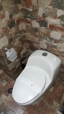 a white toilet in a bathroom with a stone wall at Cusco Bed and Breakfast in Cusco