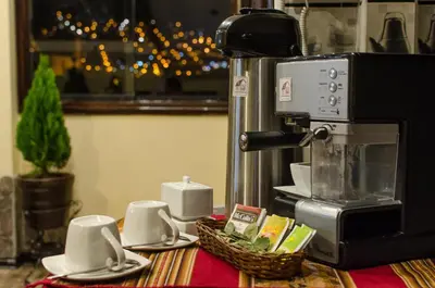 a counter with cups and saucers and a coffee maker at Cusco Bed and Breakfast in Cusco